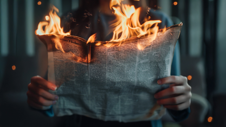 An image of a person reading a burning newspaper